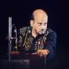 Artist intensely playing keyboard during an Indian classical music performance.
