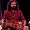 Patri Satish Kumar performing on stage, playing the mridangam during a concert.