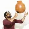 Chandrasekara Sharma holding a clay pot instrument during a performance.