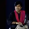 Prashant Pandav Tabla artist performing on stage in black attire with a red stole.