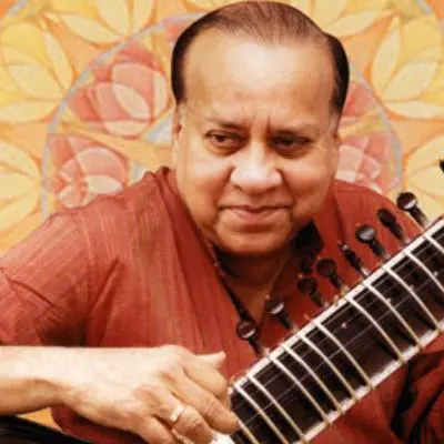 Portrait of a sitar performer playing the instrument in a close-up view.