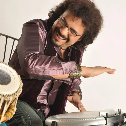 Bickram Ghosh playing tabla and electronic percussion with a joyful expression.
