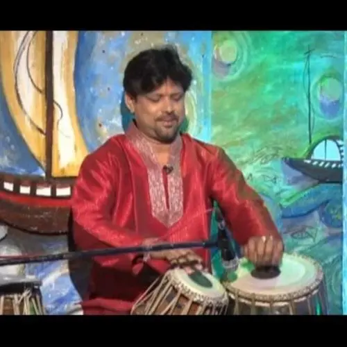 tabla player performing live on stage against colorful artistic backdrop