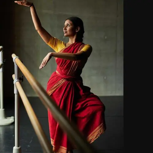 Indian classical dancer Bhavana Reddy practicing Kuchipudi dance at a ballet barre in a studio.