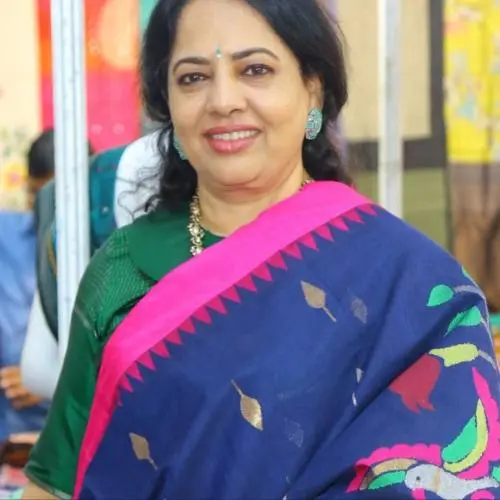 Portrait of Indian classical dancer Gaddam Padmaja wearing a blue saree with a pink border and green blouse, smiling at an event.