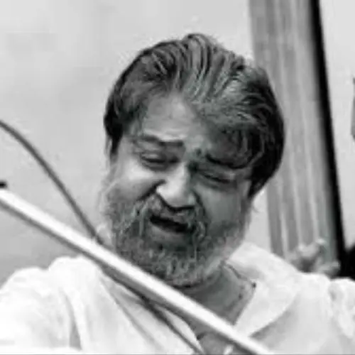 Hindustani classical vocalist Mukul Shivputra singing during a live performance, captured in a black-and-white photograph with a raised hand gesture near a microphone.