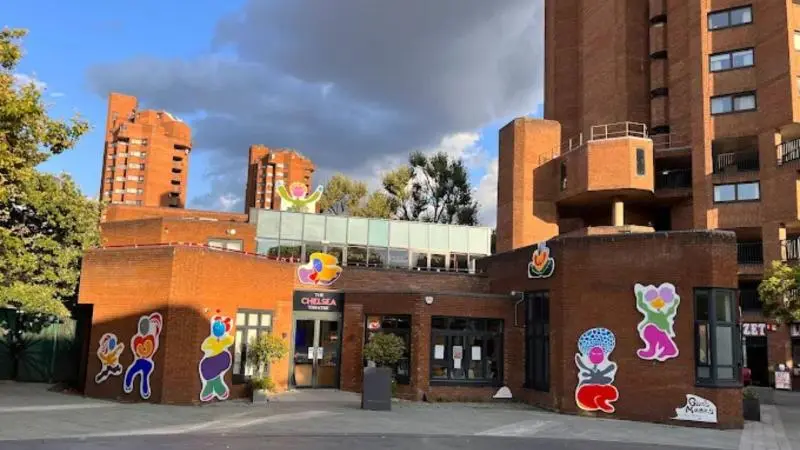 Front view of Chelsea Theatre with modern brick architecture and large colourful character murals on the exterior.