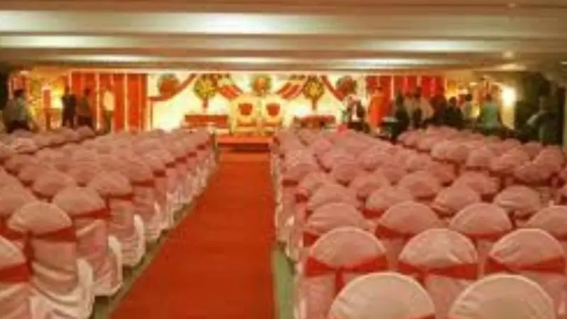 Interior of Dadar Matunga Cultural Center hall in Mumbai, showing rows of decorated chairs with red sashes facing a stage set up for an event.