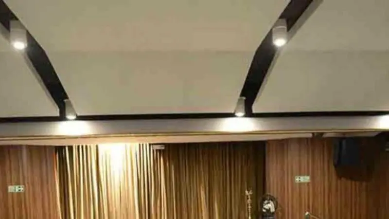Stage with closed curtains and seating area inside Kasturi Srinivasan Hall at The Music Academy.