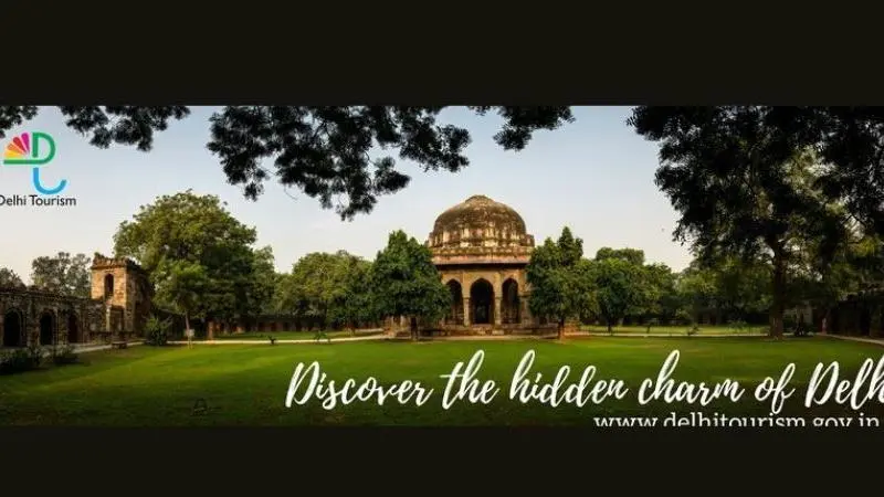 Delhi Tourism banner featuring a historic Mughal-era monument surrounded by lush greenery with the text “Discover the hidden charm of Delhi.”
